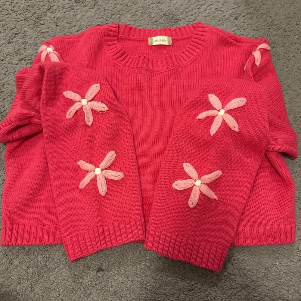 Cute cropped hoodie with knitted flowers on the sleeves.